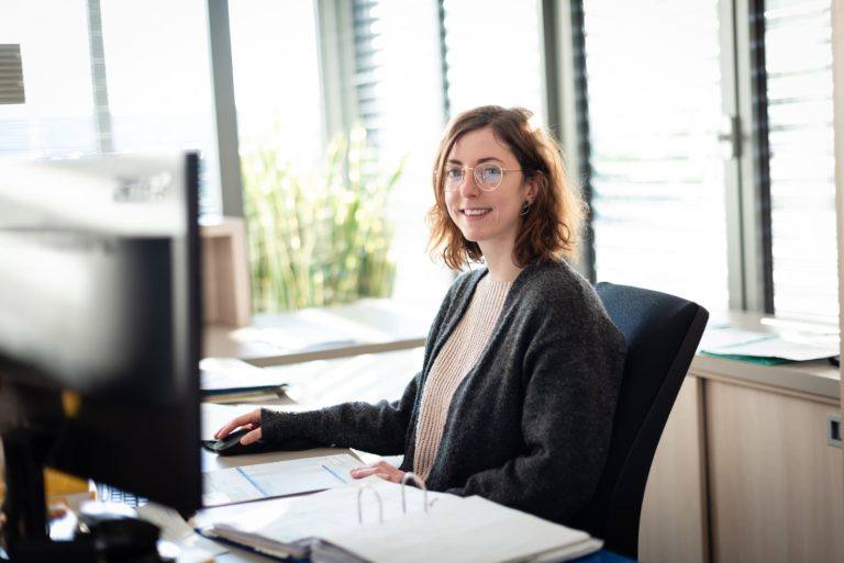 Femme assise devant un ordinateur membre de la partie administrative du groupe Vincentz